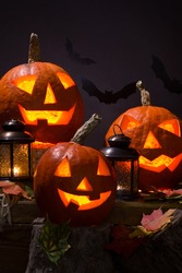 halloween pumpkins, near lanterns and  bats on dark background