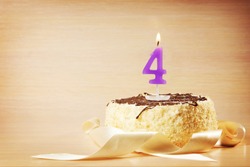 Birthday cake with burning candle as a number four. Focus on the candle
