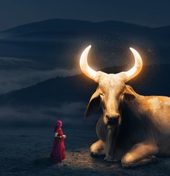 Woman in red sari worships big Holy Cow with glowing golden magic horns in Rajasthan, India