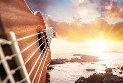 Guitar player at seascape sunset background 