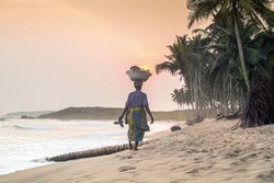 African woman at beautiful sunset on a paradise beach, West Africa
