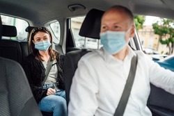 Taxi driver in a mask with a client on the back seat wearing mask