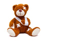 Teddy bear with bandages and broken hand isolated on white background