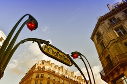 Metro station sign in Paris with beautiful background sky.