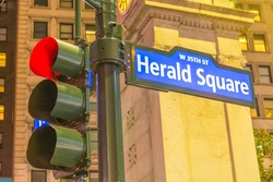 Herald Square street sign and traffic light in Manhattan at night.