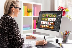 Woman working with digital photo library on desktop computer and editing photos