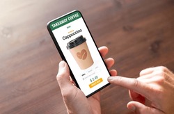 Person ordering coffee online for takeaway on mobile phone
