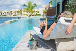 Lady relaxing in deck chair by the pool and drinking champagne