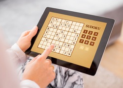 Woman playing Sudoku on tablet computer