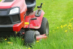 Mowing or cutting the long grass with a lawn mower . Gardening concept background .