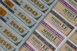 US Savings Bonds and 100 Dollar bills, representing investment choices. Savings bonds are debt securities issued by the U.S. Department of the Treasury and issued in Series EE or Series I.