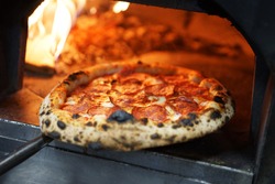 Neapolitan pizza with sausage in a wood-fired oven