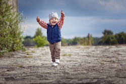 Cute little boy running and smiling with hands up