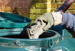 Closeup of man filling a bunded oil tank with domestic heating oil (kerosene) at a house in rural England, UK