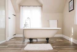 Bathroom interior, luxury modern bathroom design with roll top bathtub and a window in the background, UK