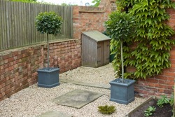 Standard bay trees in containers at the entrance to a passageway or narrow garden. UK landscaped garden design.