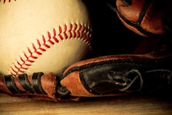 Baseball - This is a close up shot of an old baseball inside an old baseball glove on a wood background. Shot in a warm retro color tone.