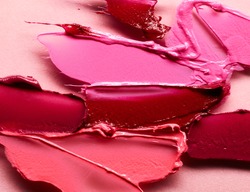 Smudged lipsticks different colors over pink background
