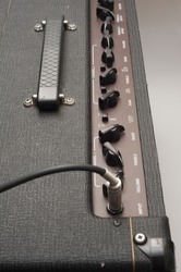 Close-up detail showing a guitar jack cable plugged into the input socket of a classic British Vox AC30 vintage valve guitar amplifier. The chicken head knobs are visible in the background.