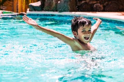 Young boy kid child eight years old splashing in swimming pool having fun leisure activity open arms
