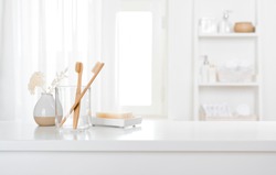 Table with toothbrushes and soap inside a bright defocused bathroom