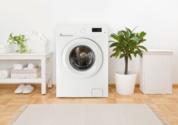 Modern washing machine, towels and related objects in laundry room