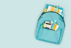 School backpack with different colorful stationery products on blue background