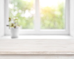 Wooden table on defocused summer window with flower pot background