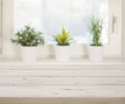 Wooden table on blurred winter window with plant pots background.