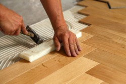 Worker laying parquet flooring. Worker installing wooden laminate flooring
