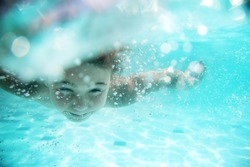 child swimming underwater in sea or pool