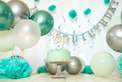 sliver, blue and white decoration for a 1st birthday cake smash studio photo shoot with balloons, paper decor, cake and topper. High quality photo