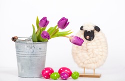 Easter holiday background of colorful Easter eggs, pink tulips in bucket and cute little sheep