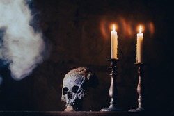 Real human skull with candles in the darkness. Spooky, horror wallpaper for Halloween.
