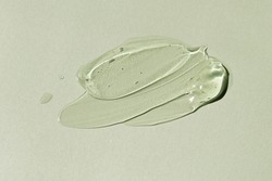 Liquid gel smear isolated on grey green background. Beauty cosmetic smudge such as pure transparent aloe lotion, facial jelly serum, cleanser, shower gel or shampoo top view.