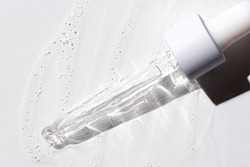 Liquid oil serum drop in pipette isolated on white background. Retinol, aha, bha acid, collagen skincare fluid, photo with shallow depth of field. Gold essence in dropper for beauty treatment.