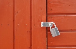 padlock on locked door of red wood cabin or wooden shed