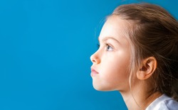 Studio closeup portrait of little girl with serious face in profile