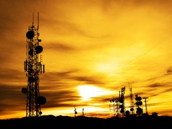 Several radio towers with sunset sky in background