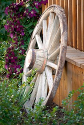 Old wagon wheel against fence in flower garden for decoration landscaping