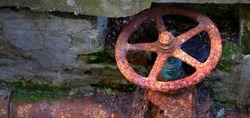 Old rusted and broken iron water pipe with valve turn wheel rust