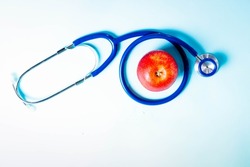 Healthcare concept - stethoscope and red apple on blue background