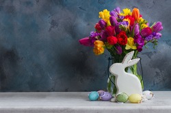 Spring fresh flowers with easter eggs and white pocelane rabbit with copy space on black background