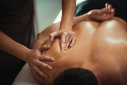 Physiotherapist massaging male patient with injured shoulder blade muscle. Sports injury treatment.