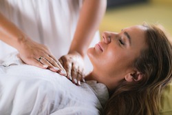 Hands of a Reiki Therapist over Patient’s Chest, Cleaning Heart Chakra. Peaceful Woman Lying with Her Eyes Closed.