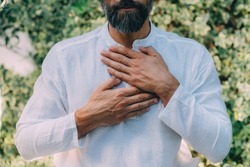Reiki spiritual self-treatment healing session. Man holding hands above the heart chakra.  