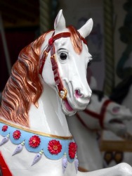 carousel horse, sharp and bright, with a darker, blurred background of another carousel horse
