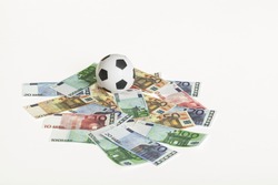 black and white colored soccer ball on a white background with euro banknotes, concept for sport and business