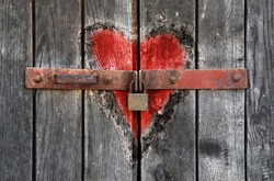 Engraved heart in the old wooden door with padlock