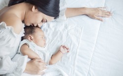 Close up portrait of beautiful young asian caucasian mother day girl kissing her healthy newborn baby sleep in bed with copy space Healthcare and medical love asia woman lifestyle mother's day concept